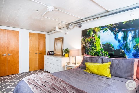 A bedroom with a bed, a dresser, and a painting on the wall.